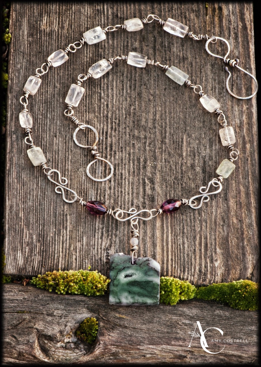 If Arthur ever forged a symbol of his love for Guinevere, he would have wreathed her delicate neck with stones of aquamarine like the sea encircles Brittania. In this version, royal purple amethyst accents moss quartz that conceals Arthur’s castle in the damp mists of history, legend, and white crystalline agate. Length: 22 inches